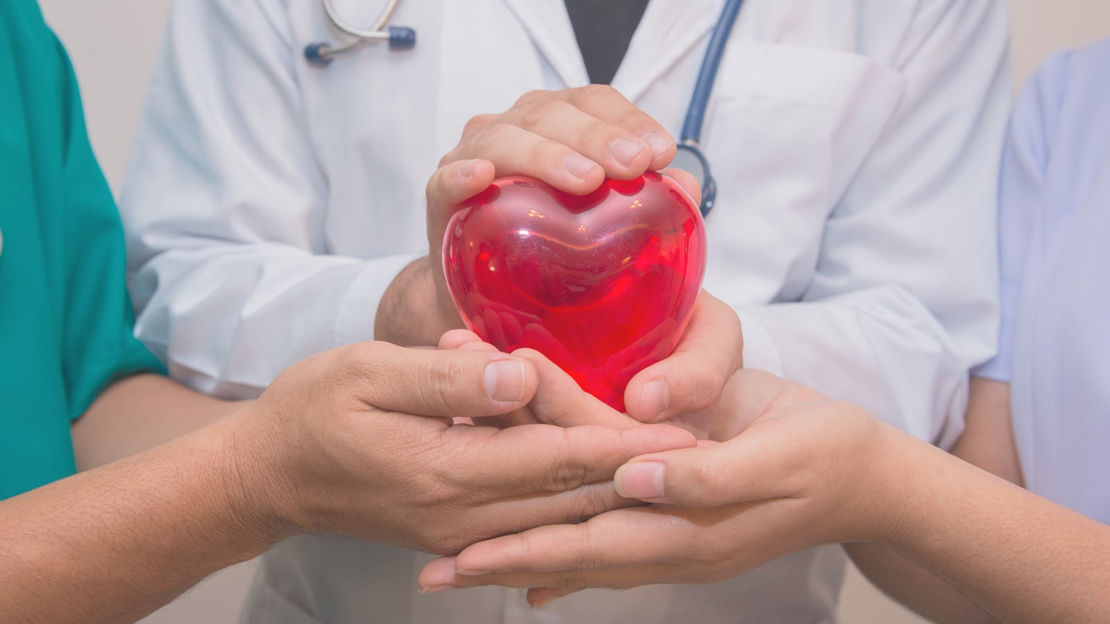 Medical team hands holding a red heart